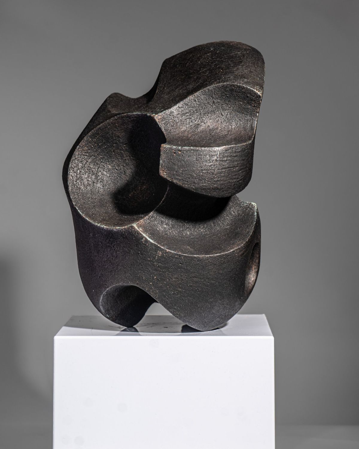Dark charcoal sculpture of interlocking curved forms